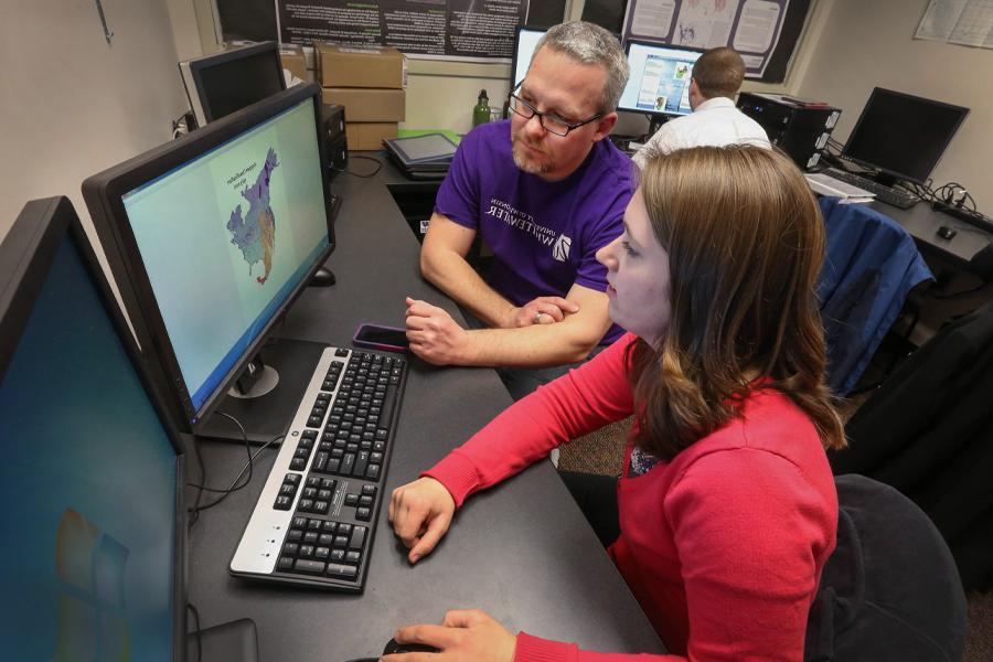 David Travis talks with a student in front of a weather poster.