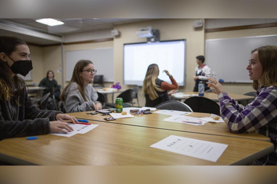 Students sit a table in a classroom.